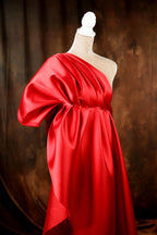 A mannequin wearing a vibrant red one-shoulder dress with a flowing, draped design.