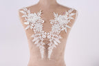 A mannequin torso with white lace flowers and leaves attached to it.