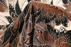 a close-up view of a fabric with a floral pattern and beaded designs in shades of brown and black.