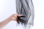 A hand is holding a black, shiny, and textured fabric, which appears to be a piece of sheer material or a decorative textile.