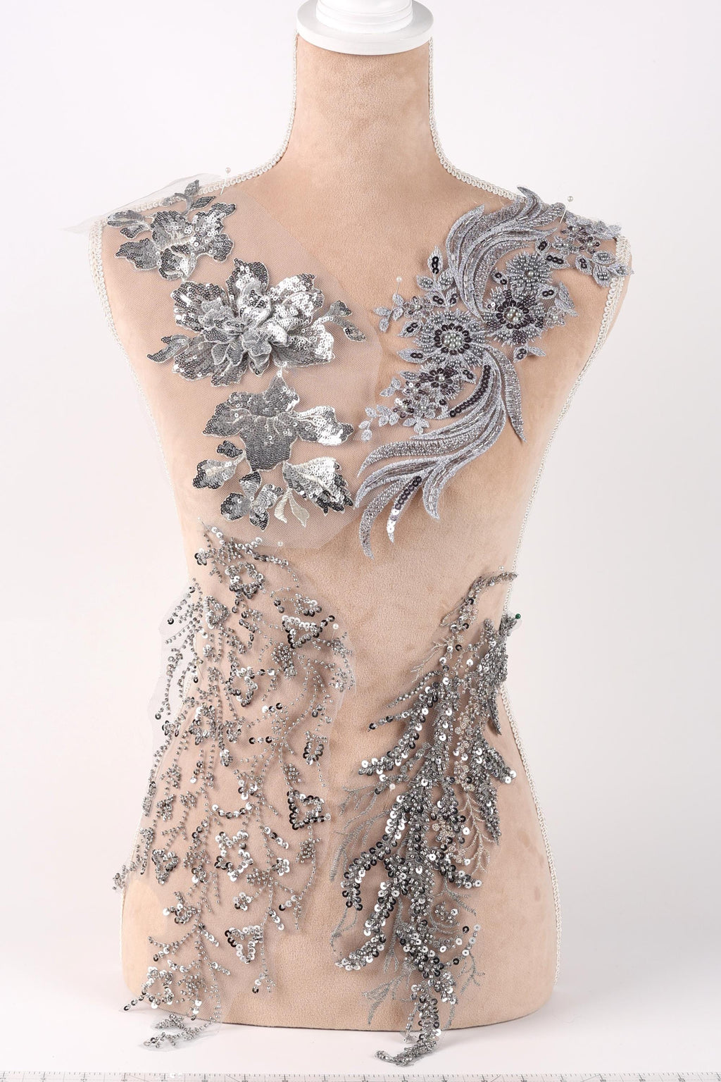 A mannequin torso with silver sequin and floral embellishments on it.