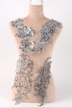 A mannequin torso with silver sequin and floral embellishments on it.