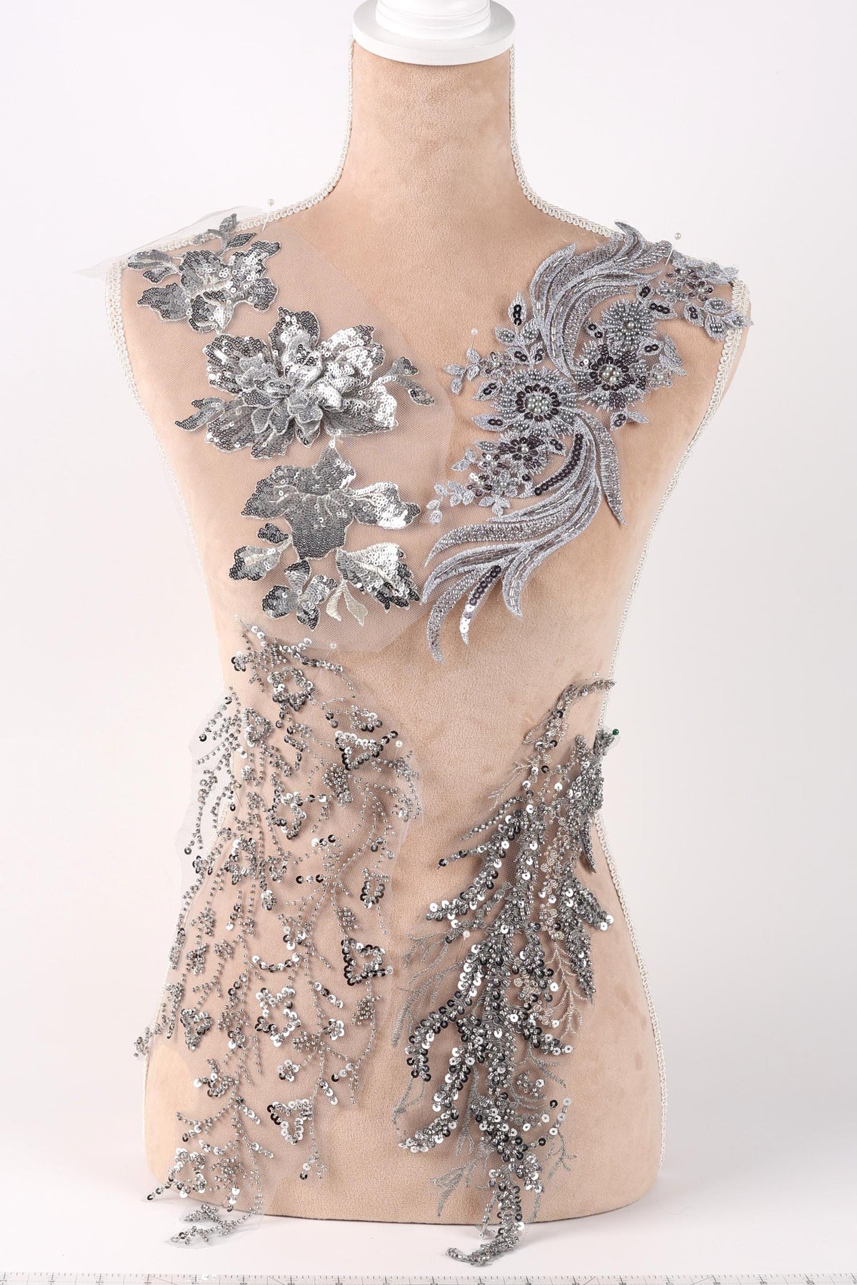 A mannequin torso with silver sequin and floral embellishments on it.