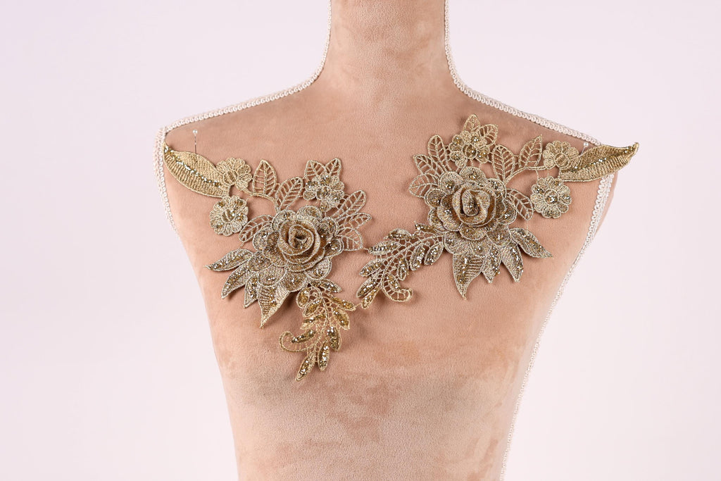 A mannequin with gold embroidered flowers on its shoulders.