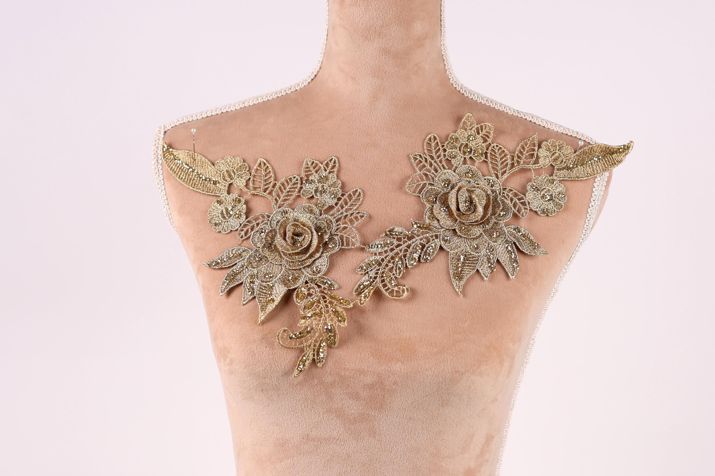 A mannequin with gold embroidered flowers on its shoulders.