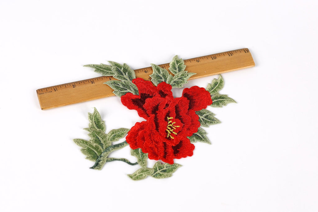 a red flower with green leaves, and a ruler is placed next to it.