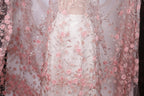 a close-up view of a delicate, sheer fabric with a floral pattern of pink roses. The fabric appears to be a sheer white dress or garment, with the pink roses adding a touch of elegance and softness to the overall design.