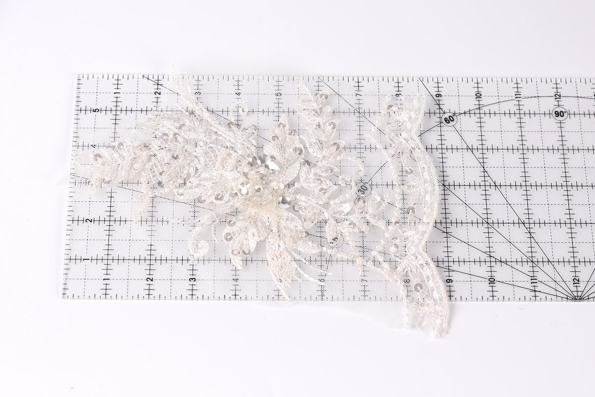 a piece of white lace with intricate patterns, placed on a transparent ruler.