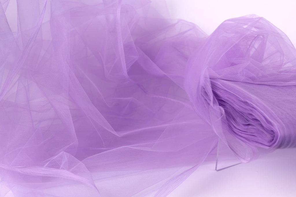 The image is a close-up of a soft, flowing fabric in a light purple color, resembling a delicate tulle or chiffon.