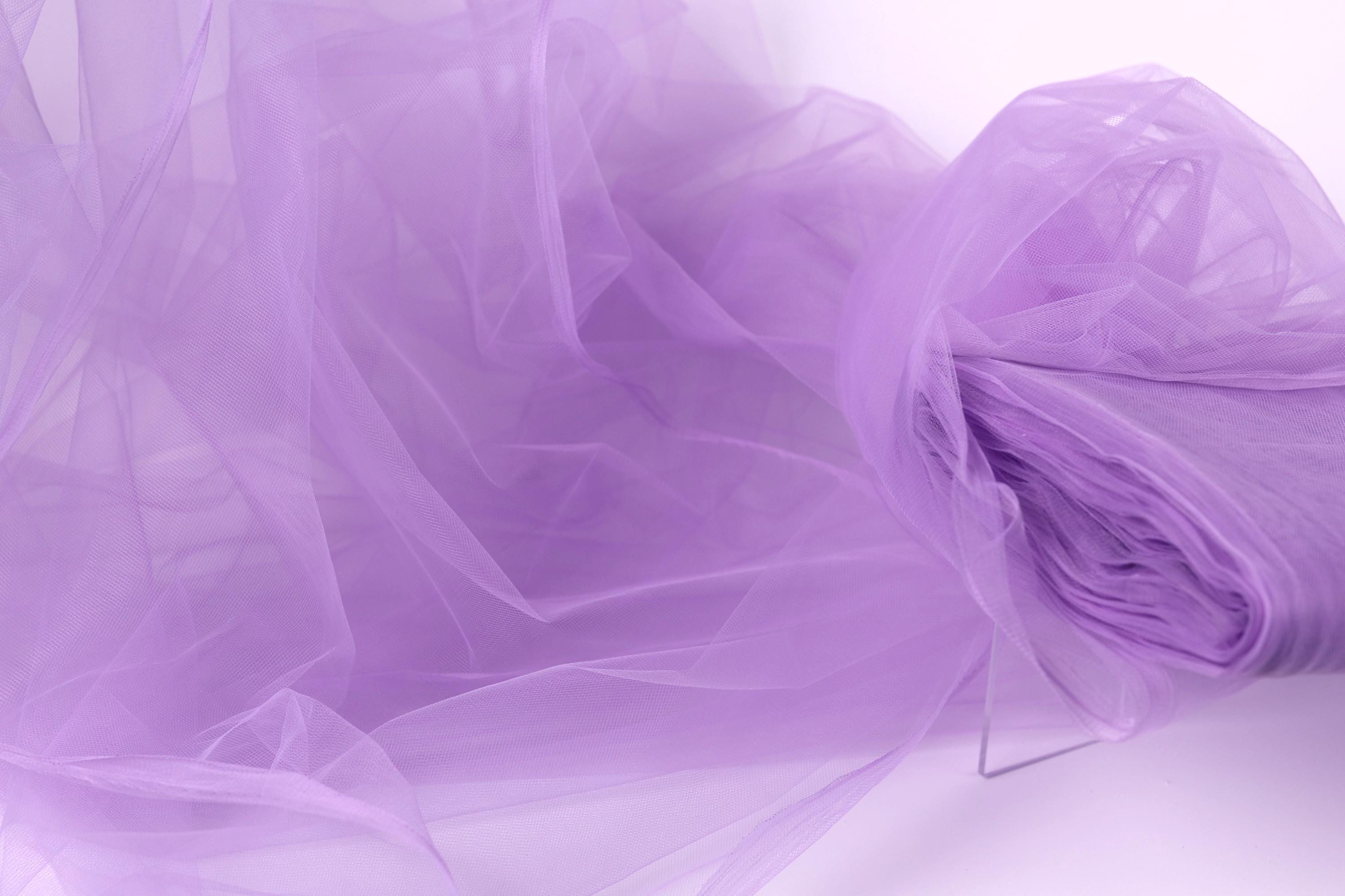 The image is a close-up of a soft, flowing fabric in a light purple color, resembling a delicate tulle or chiffon.
