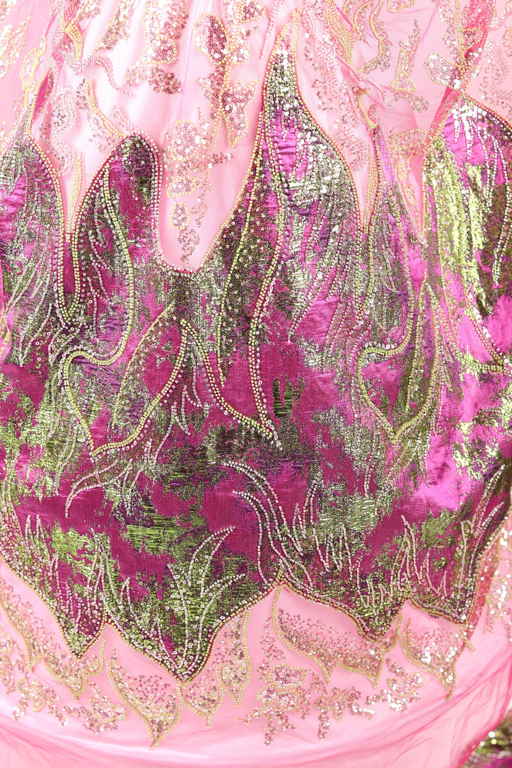 The image is a close-up of a pink and green sequined dress, showcasing intricate patterns and designs.