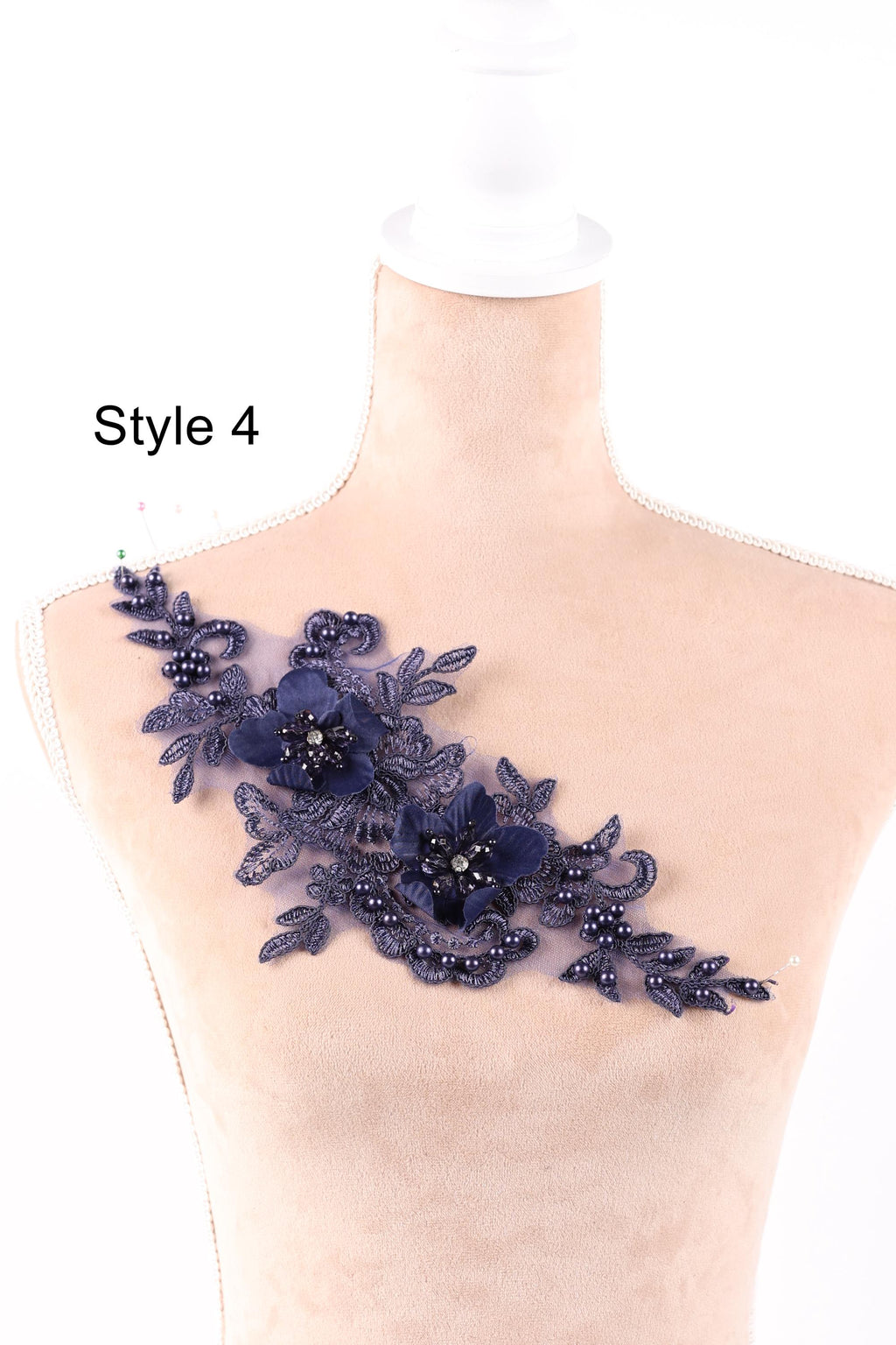 A mannequin wearing a dress with a decorative floral lace piece on the shoulder.