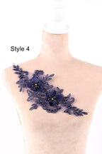 A mannequin wearing a dress with a decorative floral lace piece on the shoulder.