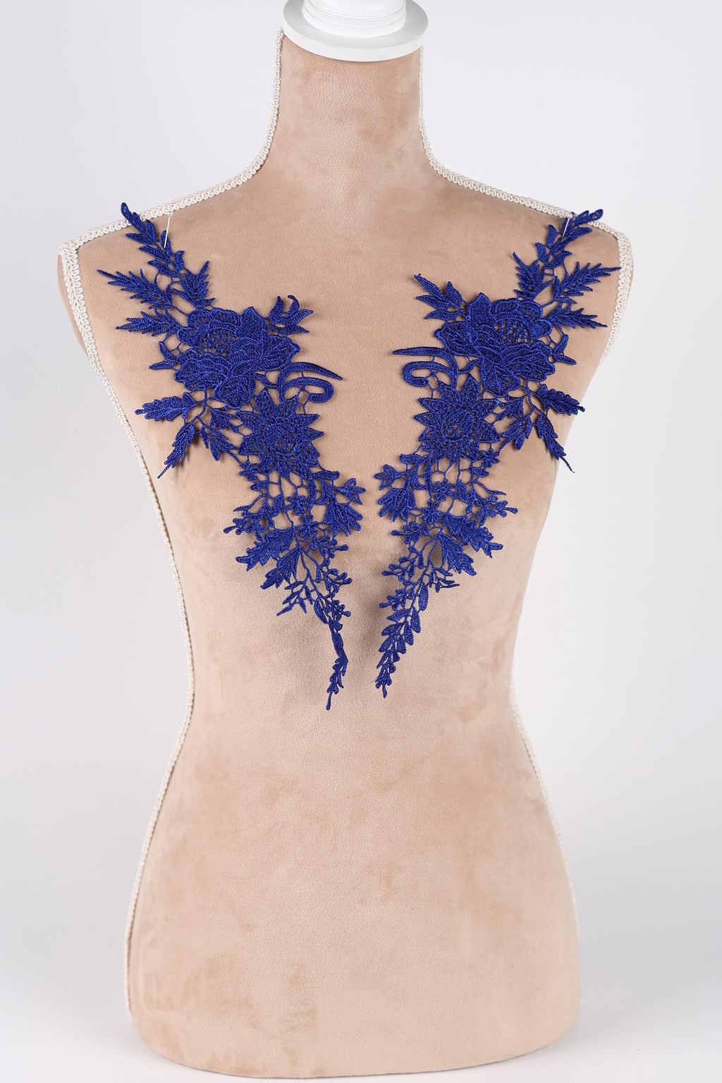 A mannequin wearing a beige dress with blue floral embroidery on the shoulders.
