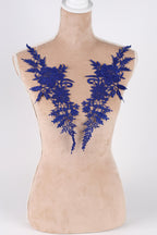 A mannequin wearing a beige dress with blue floral embroidery on the shoulders.