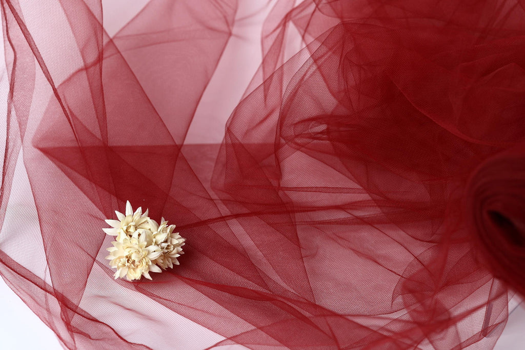 a delicate white flower resting on a red, crumpled fabric.