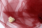 a delicate white flower resting on a red, crumpled fabric.