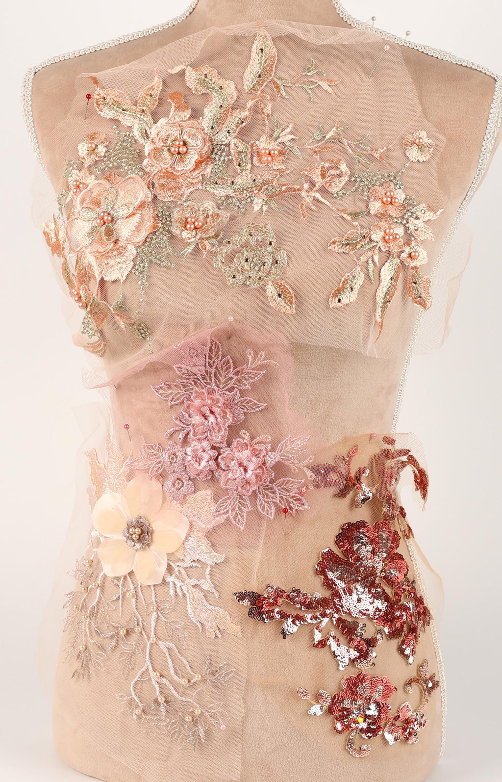 a mannequin with a beige dress adorned with various floral and sequin embellishments.