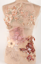 a mannequin with a beige dress adorned with various floral and sequin embellishments.