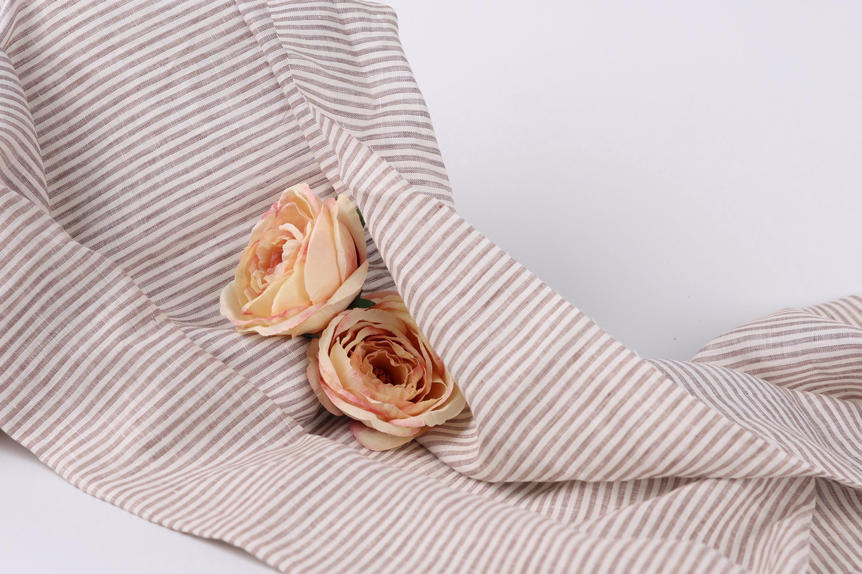Two delicate pink roses resting on a striped fabric.