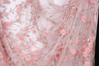 a close-up view of a delicate, pink floral fabric with numerous small pink roses and leaves. The fabric appears to be made of sheer material, giving it a delicate and airy appearance. The roses and leaves are intricately embroidered, adding a touch of elegance and detail to the fabric.