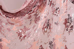 The image is a close-up of a fabric with a pink and red sequin pattern. The fabric appears to be a sheer material, with a mix of pink and red sequins arranged in a decorative manner. The image does not contain any text or other discernible objects or actions.
