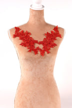 A mannequin wearing a red lace necklace with red flowers.