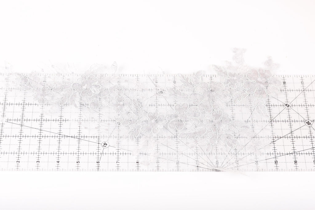 a close-up view of a white lace fabric with a grid pattern on a white background.