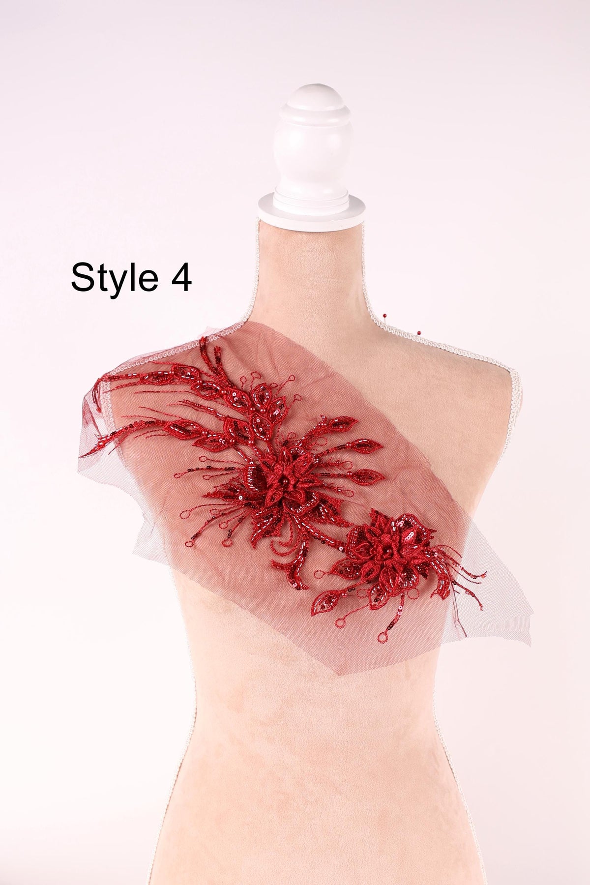 A mannequin wearing a red floral embellishment on its shoulder.