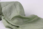 A close-up view of a fabric with green and white striped patterns, appearing crumpled and folded.
