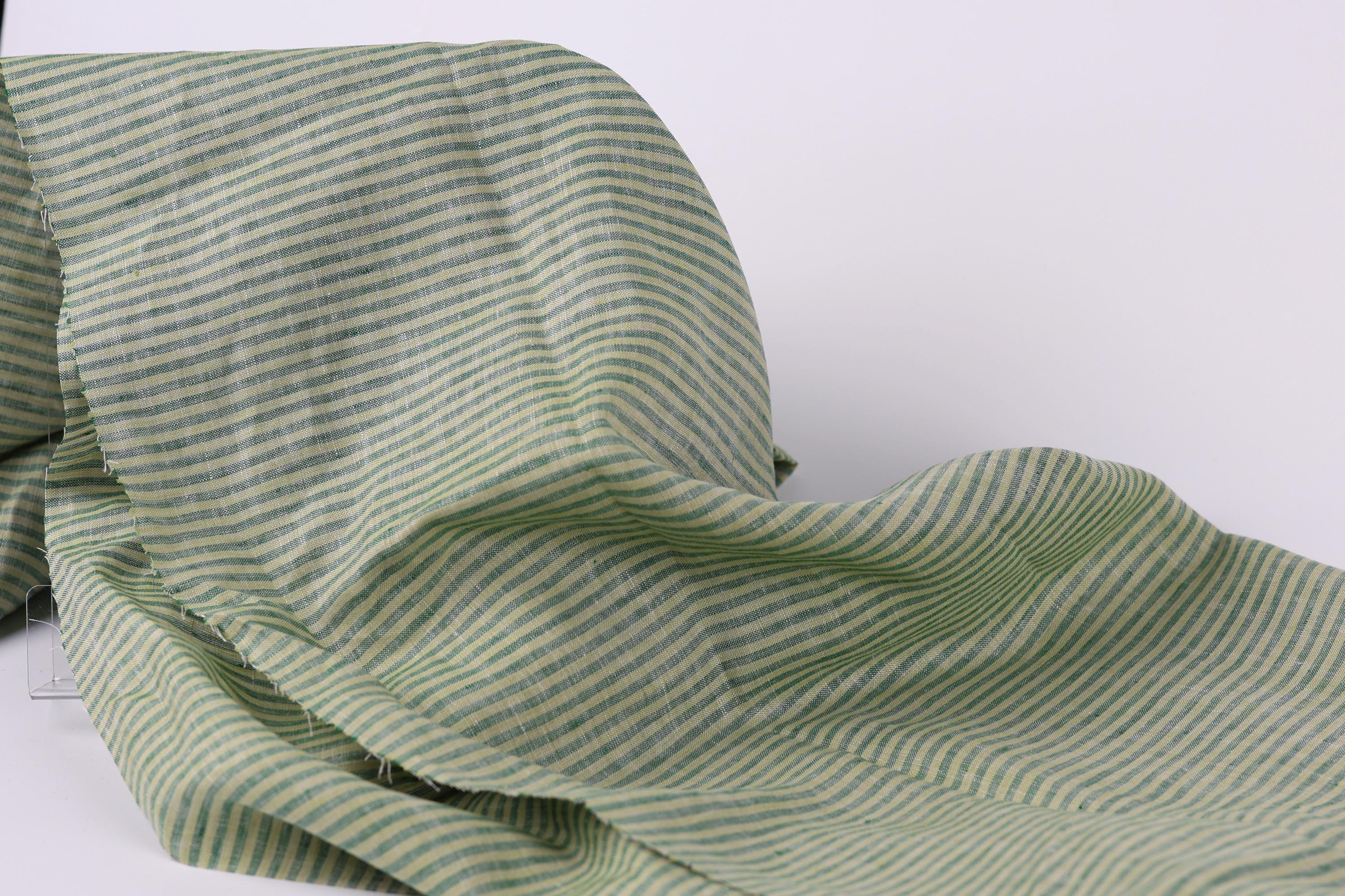 A close-up view of a fabric with green and white striped patterns, appearing crumpled and folded.