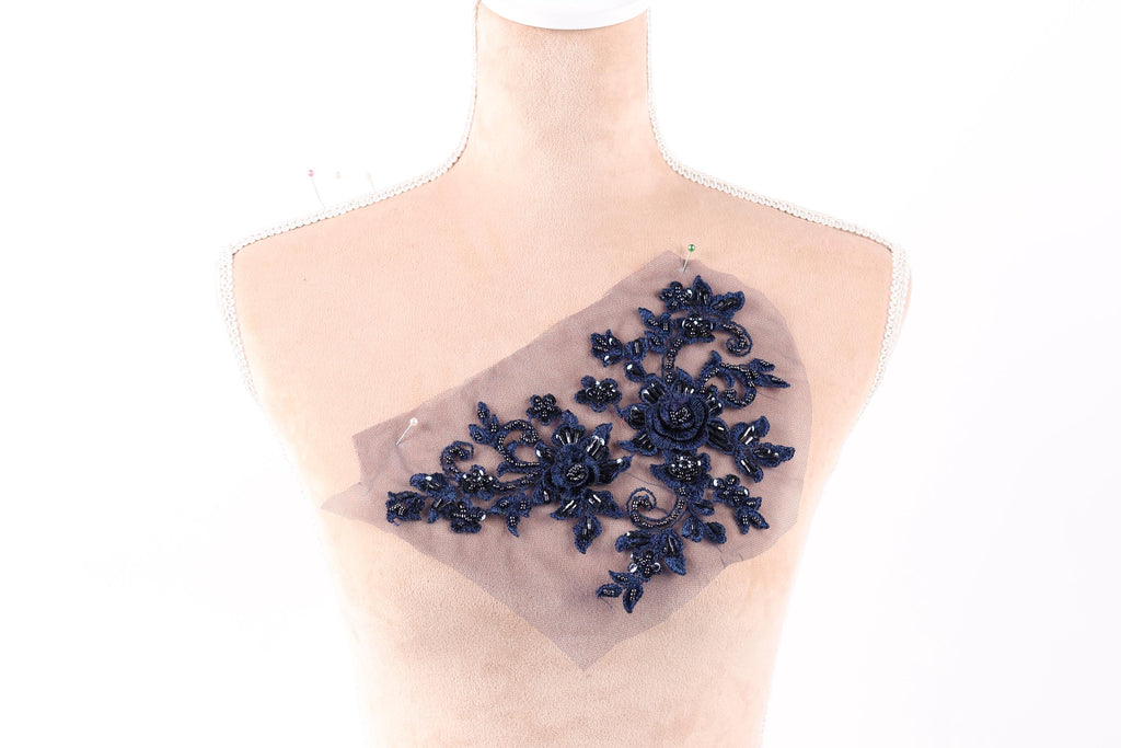 A mannequin with a decorative blue floral embroidery piece on its chest.