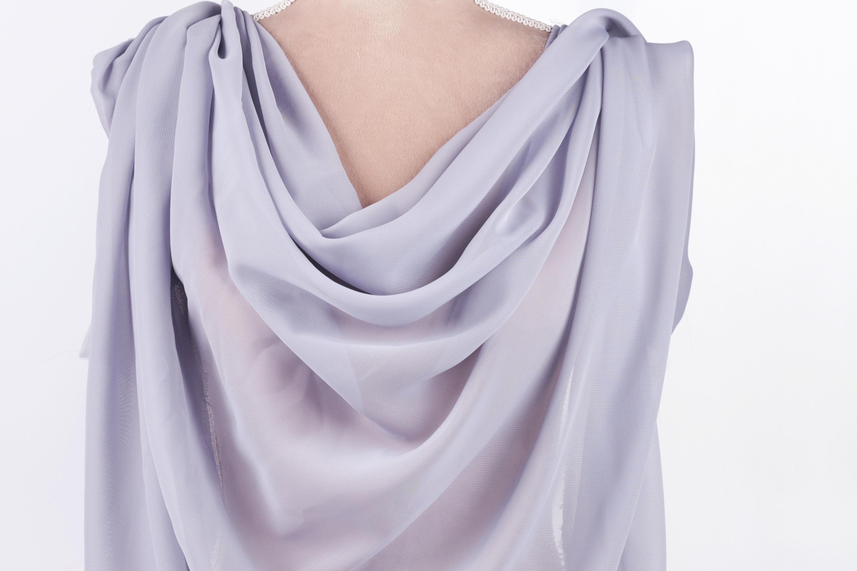 A close-up view of a draped, flowing garment in a light purple color.