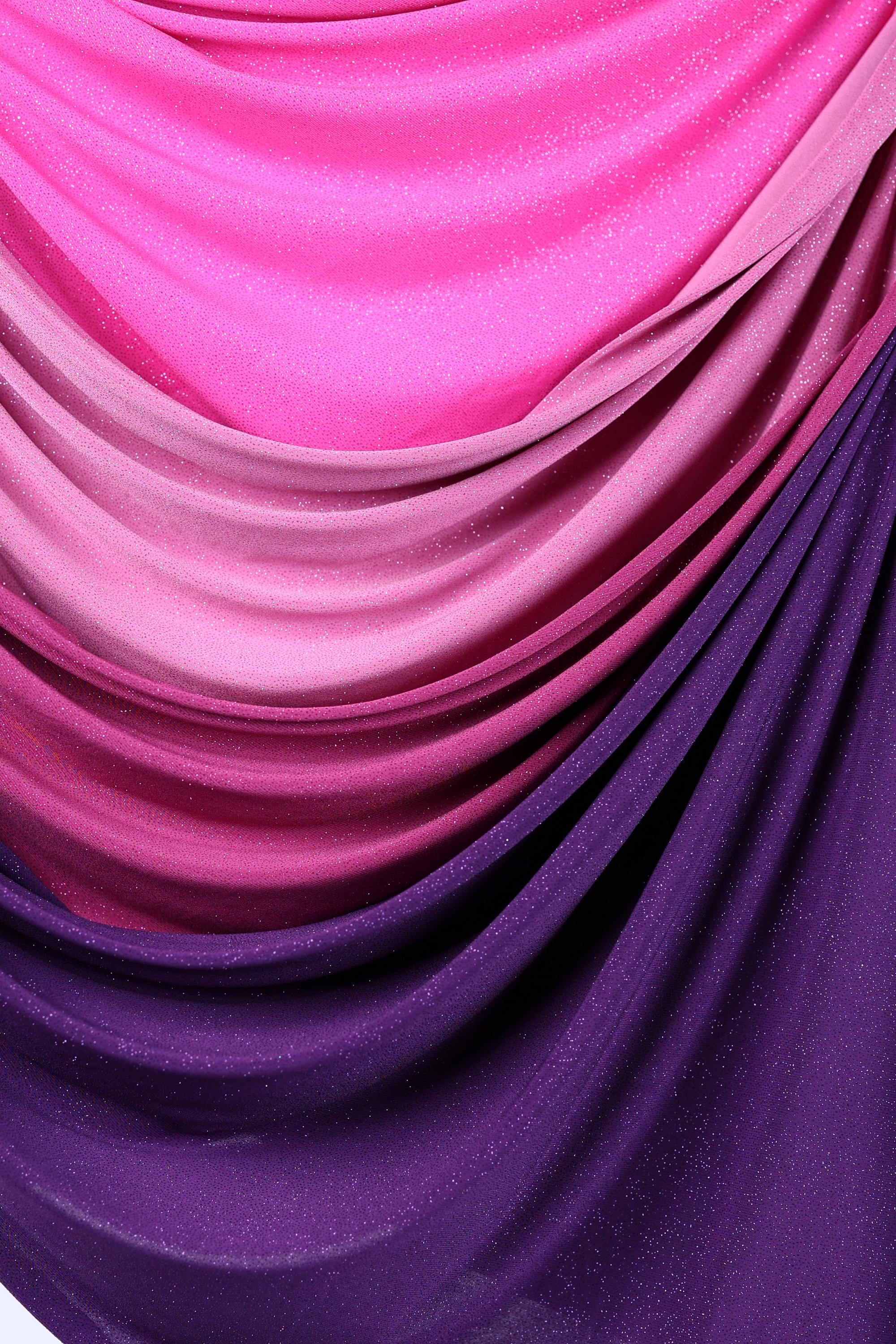 a close-up view of a fabric with a gradient of colors, transitioning from purple to pink. The fabric appears to be made of a shiny, textured material, creating a visually striking and dynamic composition.