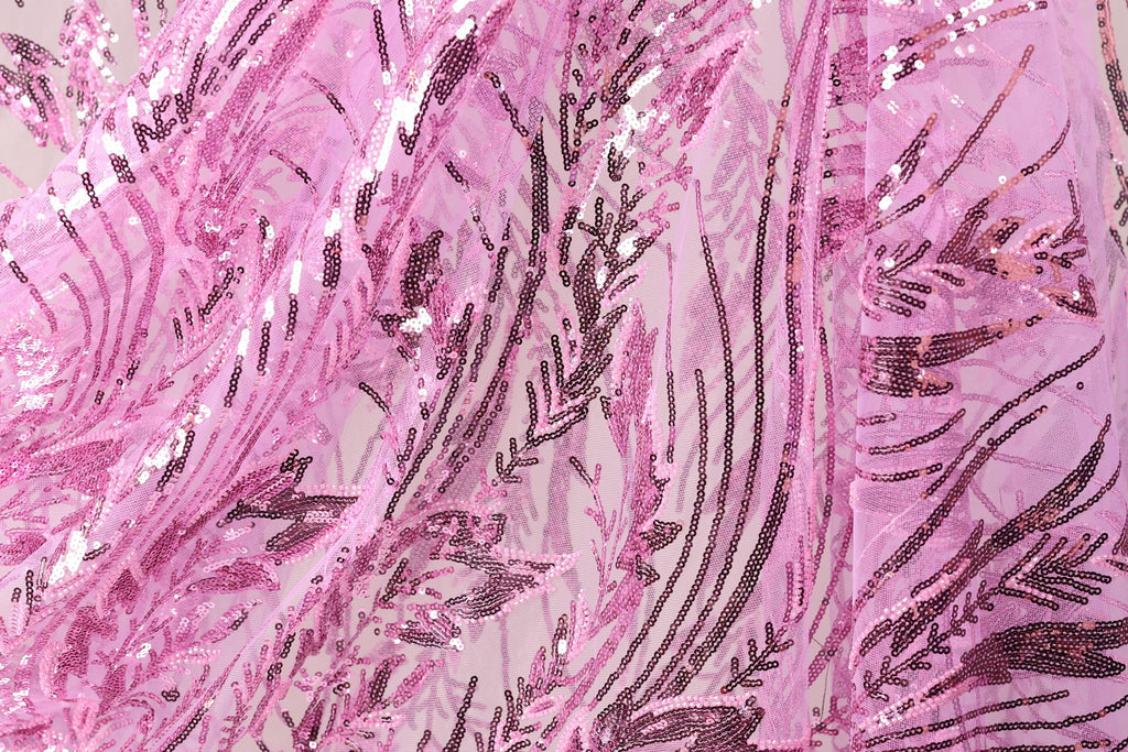 The image is a close-up view of a fabric with a pink and black sequin pattern. The fabric appears to be made of sheer material, giving it a delicate and intricate appearance. The pattern consists of various lines and shapes, creating a visually striking and textured design.