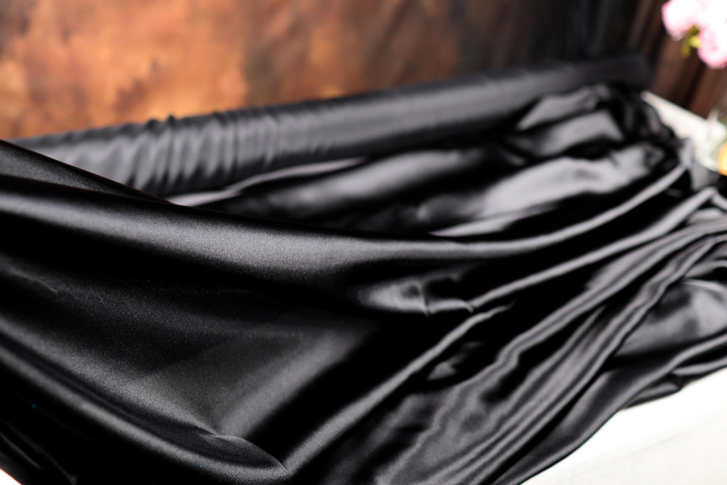 a close up of a black cloth on a bed