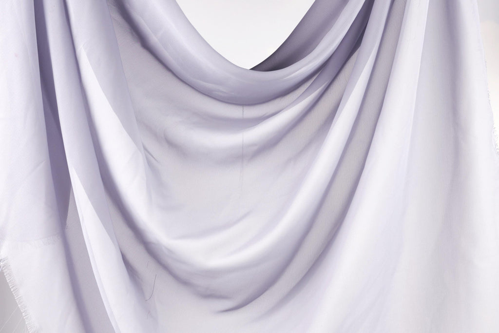 The image is a close-up of a white fabric, possibly a sheer or sheer-like material, with a soft, flowing texture.