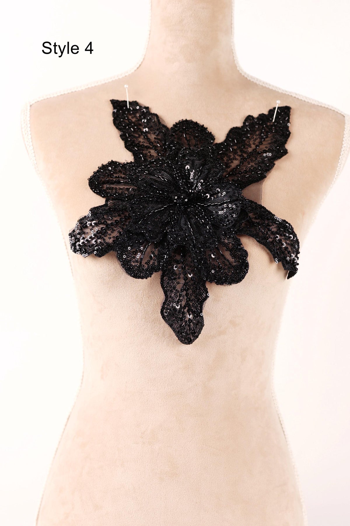A mannequin wearing a black lace flower on its bust.