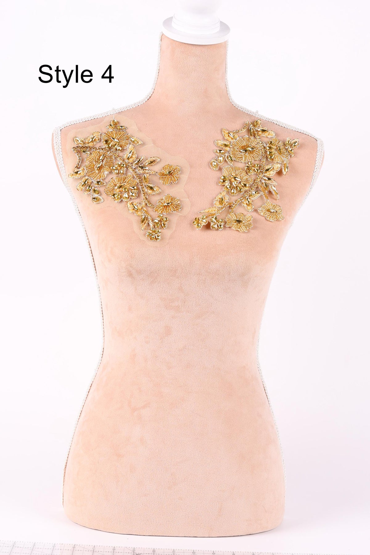 A mannequin with a beige body and gold floral embellishments on the shoulders.