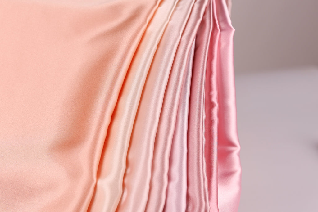 A close-up view of a soft, flowing fabric with a gradient of pink to peach colors, creating a visually appealing and textured appearance.