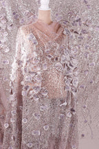a mannequin wearing a long, flowing dress with a shimmering, sequined bodice and a sheer, floral-patterned skirt. The dress appears to be made of a sheer fabric, giving it a delicate and elegant appearance.