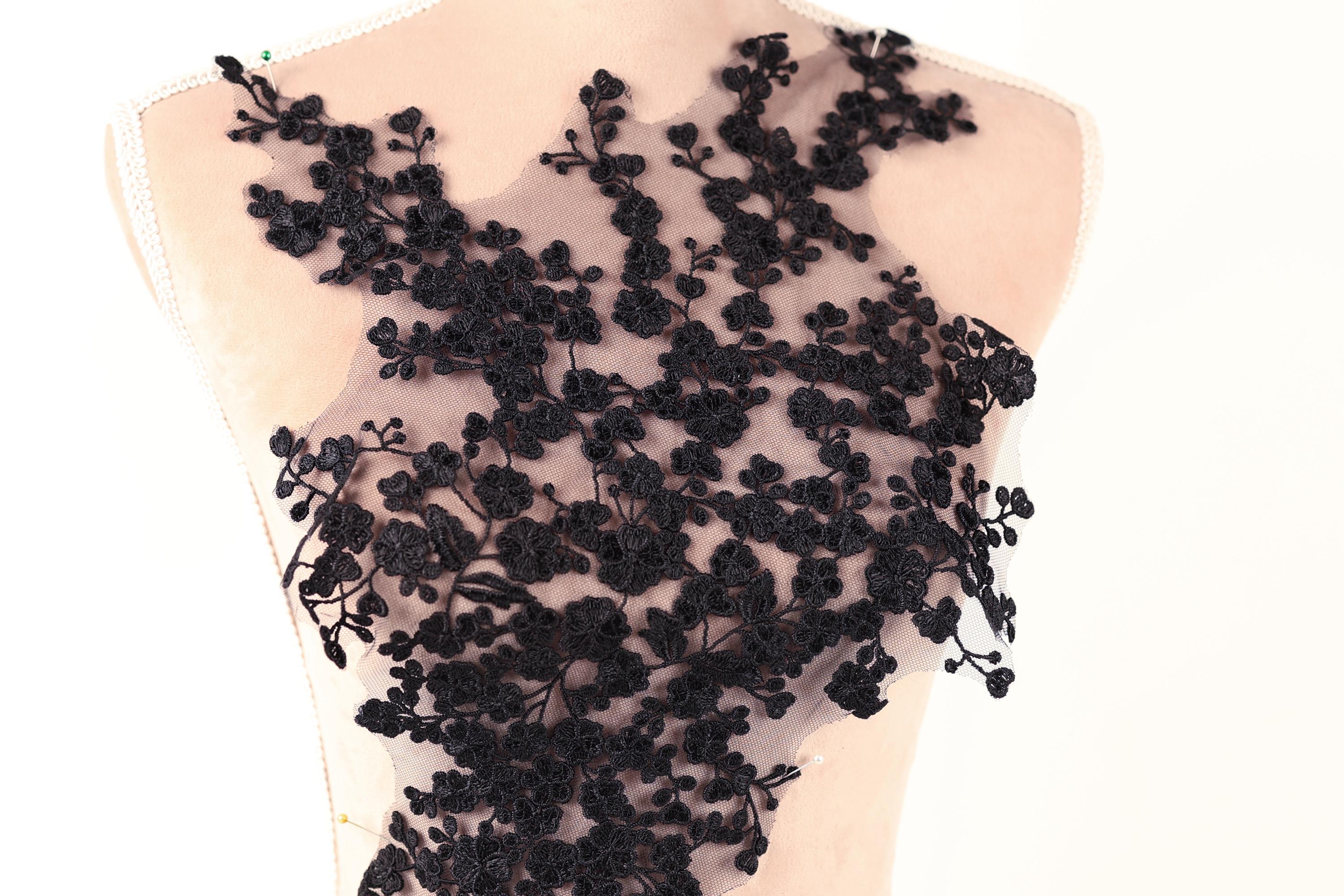 A mannequin wearing a dress with a black lace bodice featuring a floral pattern.