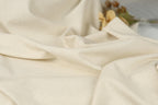 A close-up view of a soft, wrinkled fabric, possibly cotton, with a blurred background.