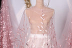 A mannequin wearing a sheer pink floral fabric with delicate pink leaves and branches.