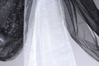 a close-up view of a white fabric with a black and white patterned design, hanging against a white background.