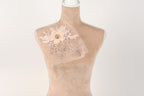 A mannequin with a delicate floral embroidered piece of fabric draped over its chest.