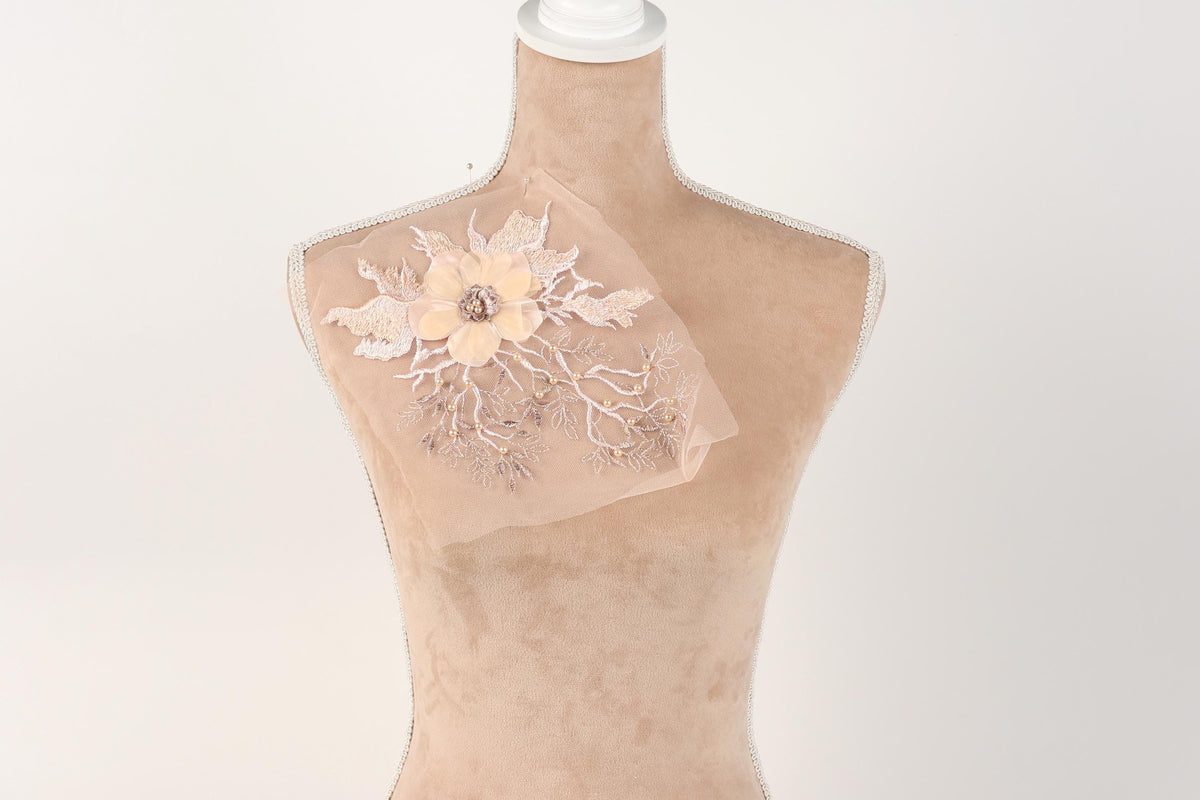 A mannequin with a delicate floral embroidered piece of fabric draped over its chest.