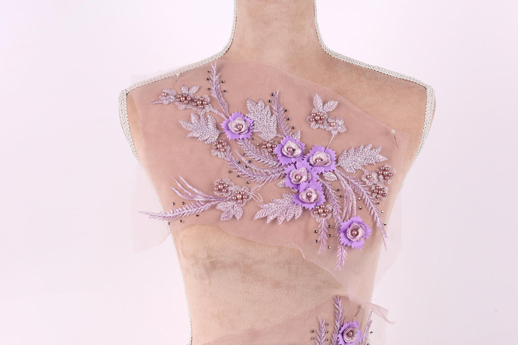 A mannequin with a delicate floral embroidered on its back, featuring a variety of purple flowers and leaves.