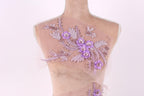 A mannequin with a delicate floral embroidered on its back, featuring a variety of purple flowers and leaves.