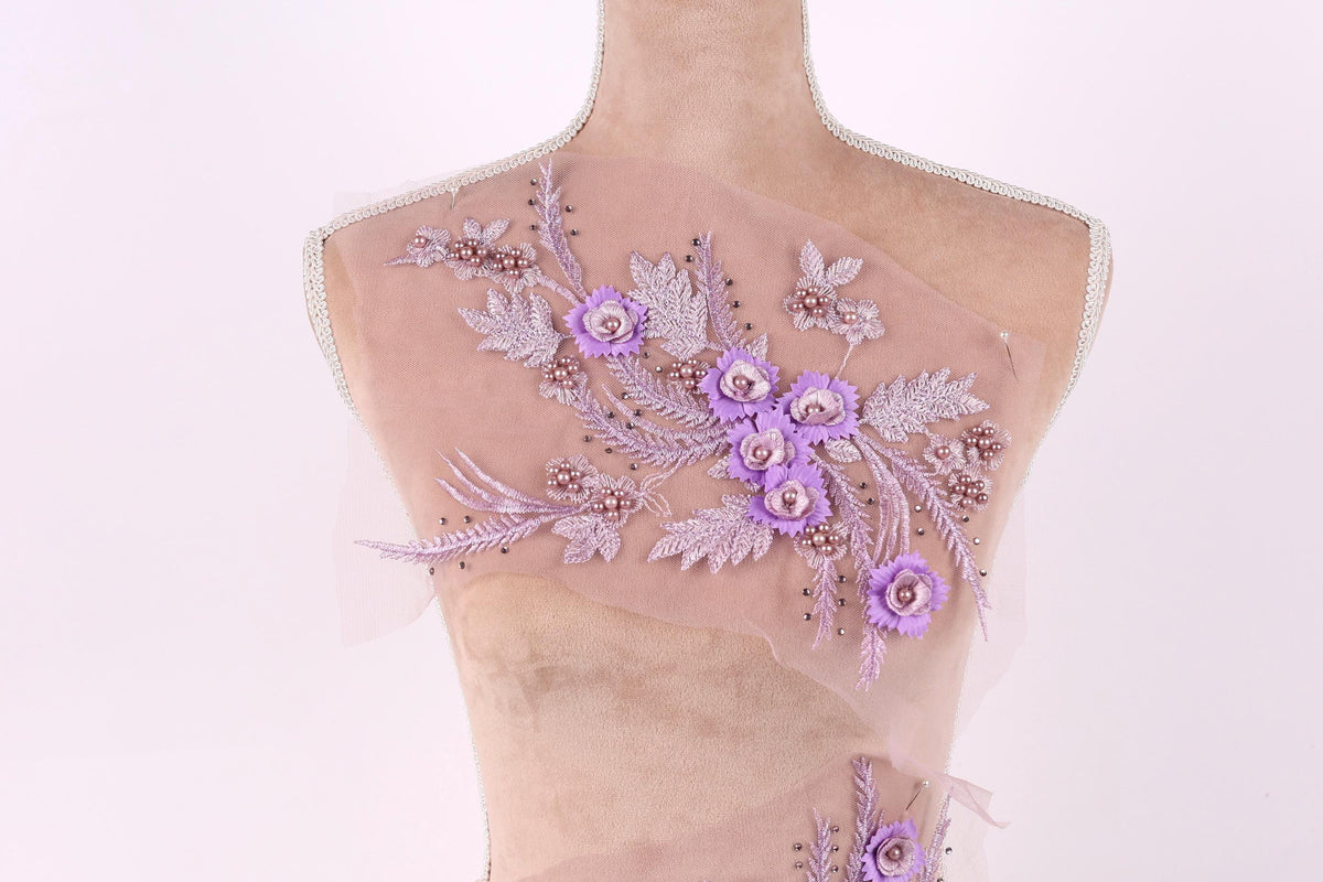 A mannequin with a delicate floral embroidered on its back, featuring a variety of purple flowers and leaves.